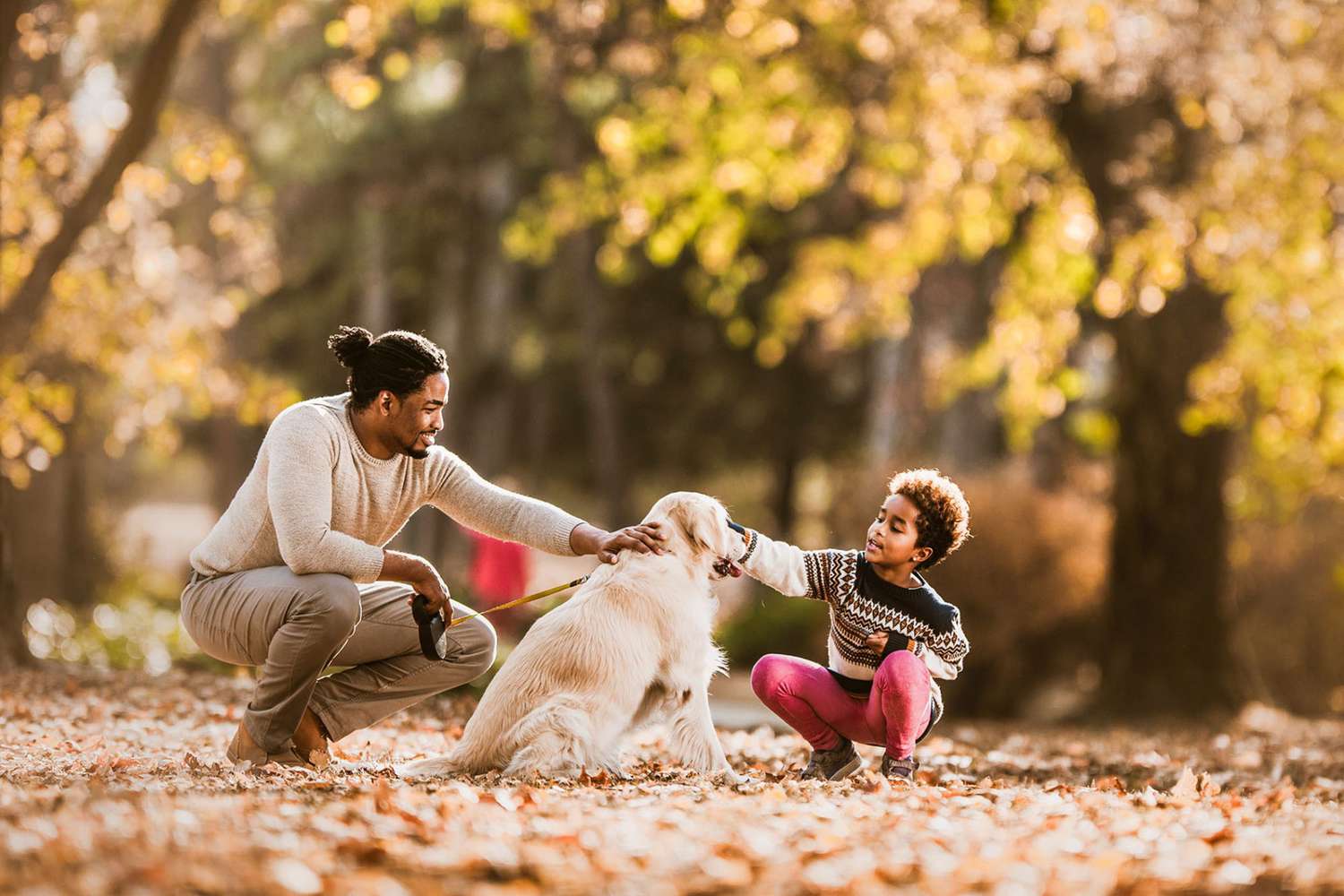 dad and son with their golden retriever in enjoying the fall foliage; fall names for dogs