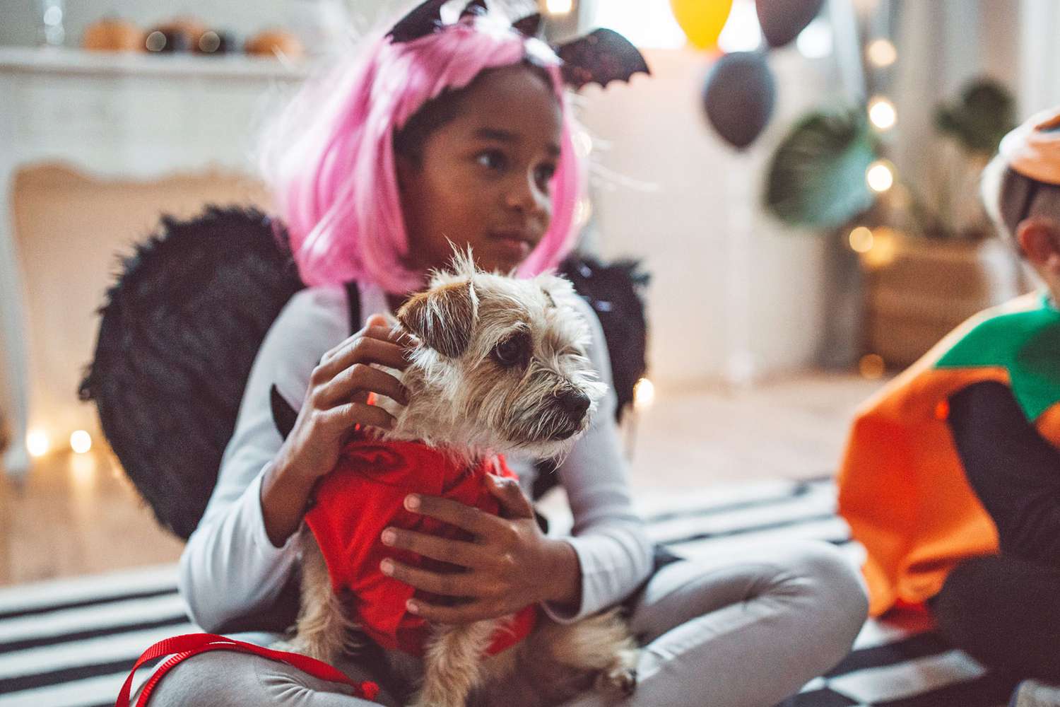 girl with dog on her lap, both in costume, at a dog Halloween party