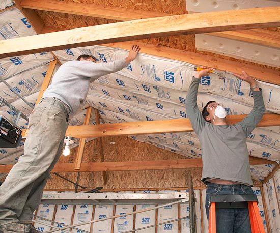 2 men putting insulation in ceiling