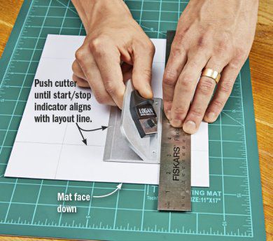 Using metal ruler to cut straight line on mat.