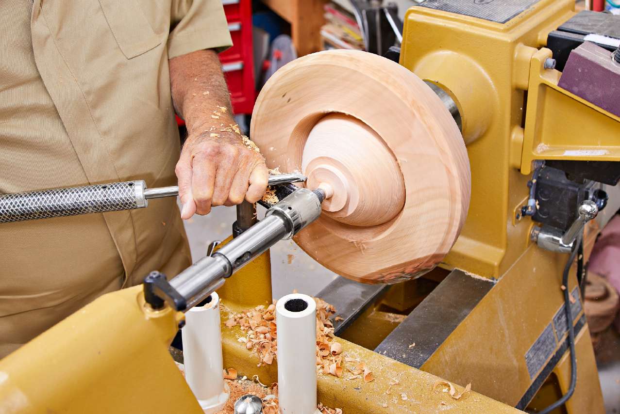 Flip the bowl around and fit it into the blank recess, using it as a jam chuck. Center the bowl, and support it with the tailstock center. Position the banjo and tool rest and form a tenon.