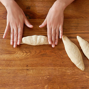 Shape the dough into 8-inch buns, plump in the center and tapered at the ends.
