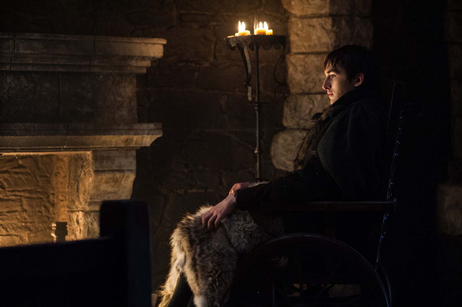 Bran Stark (Isaac Hempstead-Wright) sits by the fire, presumably at Winterfell