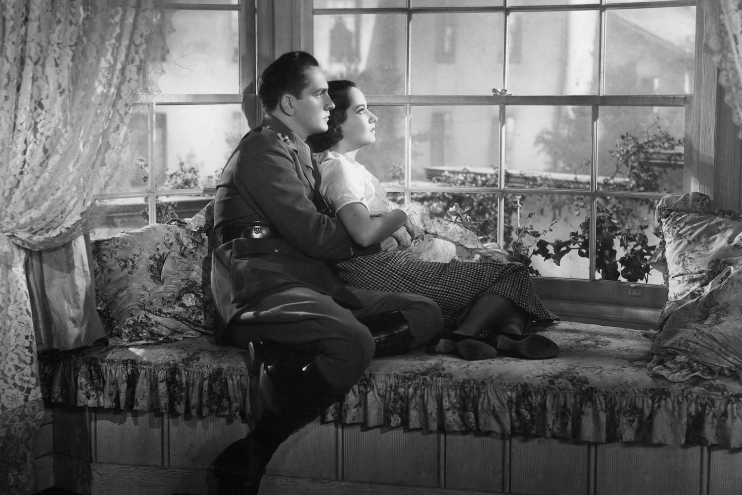 Fredric March holding Merle Oberon by the window in a scene from the film 'The Dark Angel', 1935. (Photo by United Artists/Getty Images)