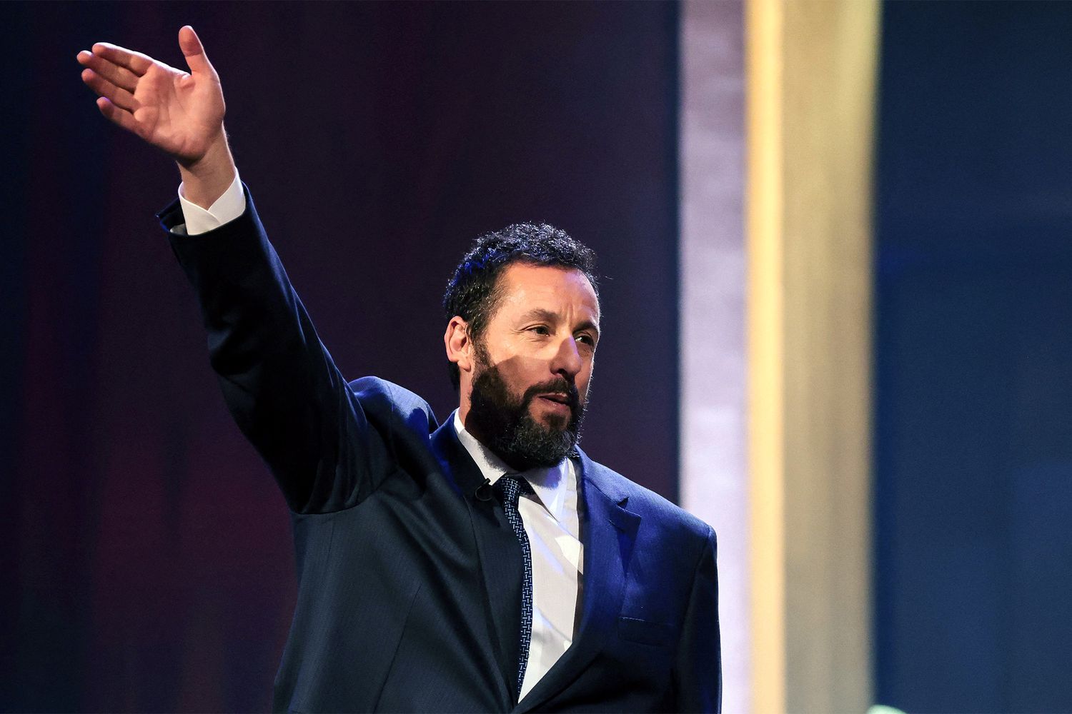 US actor Adam Sandler waves as he steps on stage during the 24th Annual Mark Twain Prize For American Humor at the John F. Kennedy Center for the Performing Arts in Washington, DC, on March 19, 2023. - This year's award is honoring US actor and comedian Adam Sandler. (Photo by Oliver Contreras / AFP) (Photo by OLIVER CONTRERAS/AFP via Getty Images)