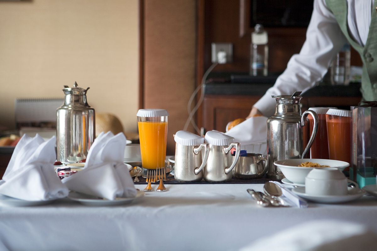 breakfast table in a hotel room with fruits and juices, coffee and tea