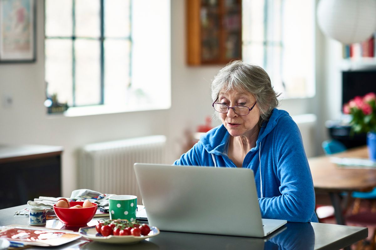 戴眼镜在家使用笔记本电脑的老年女性