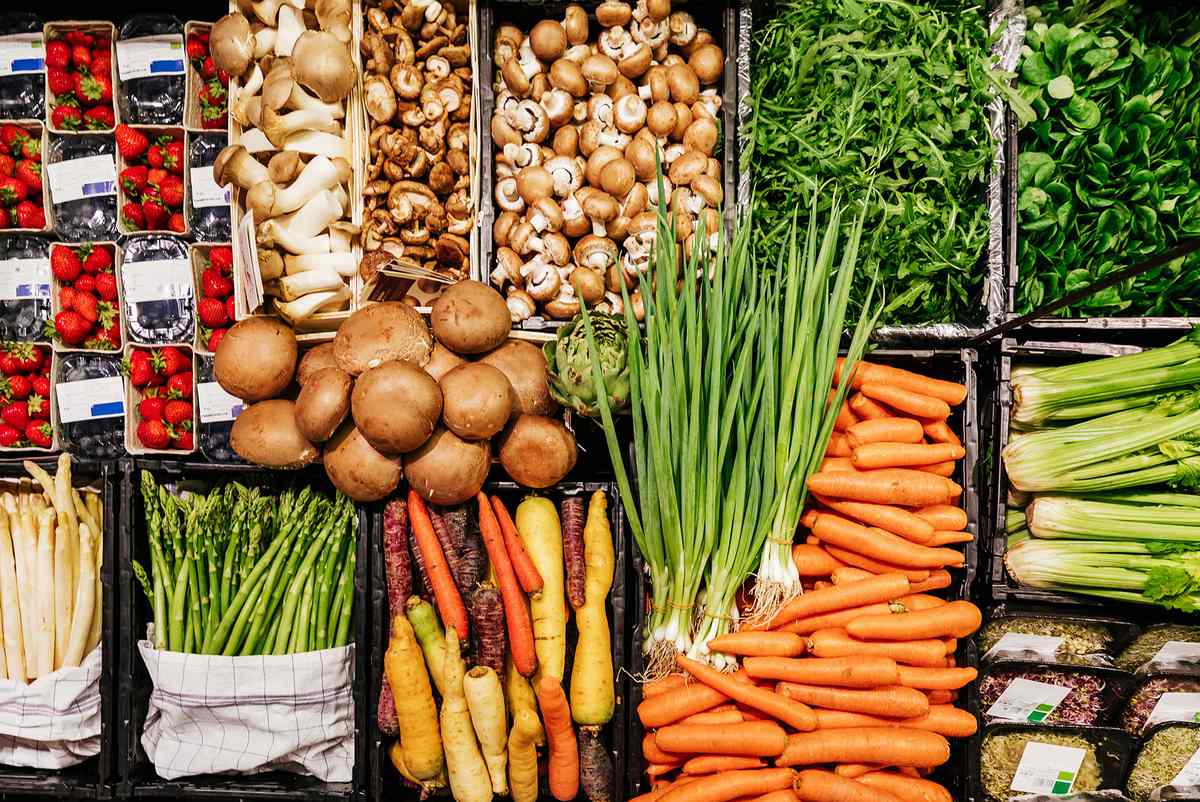 An aerial view of various vegetables, including mushrooms, carrots and asparagus at a local supermarket.