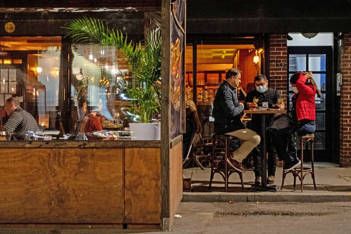 A waiter wearing a mask delivers food to customers dining outdoors in the West Village on November 20, 2020 in New York City.