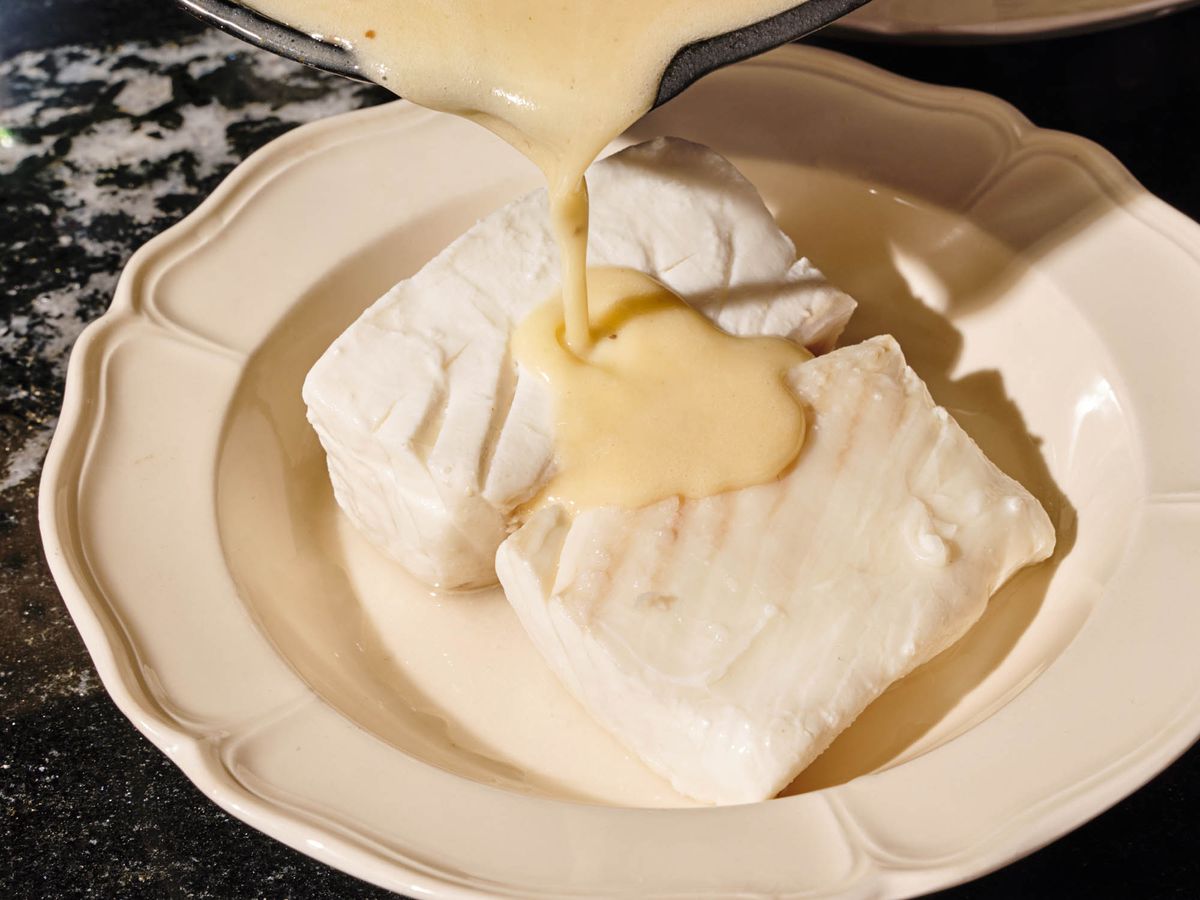 pouring butter sauce over poached halibut