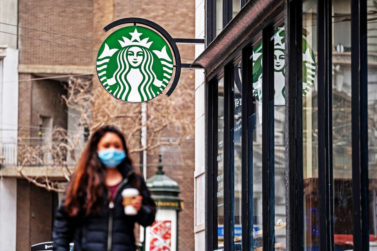 A person wearing a protective mask walks past a Starbucks coffee shop