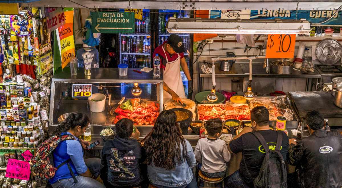 顾客在Mercado San Juanvwin德赢ac米兰 de Dios的食物摊上吃饭
