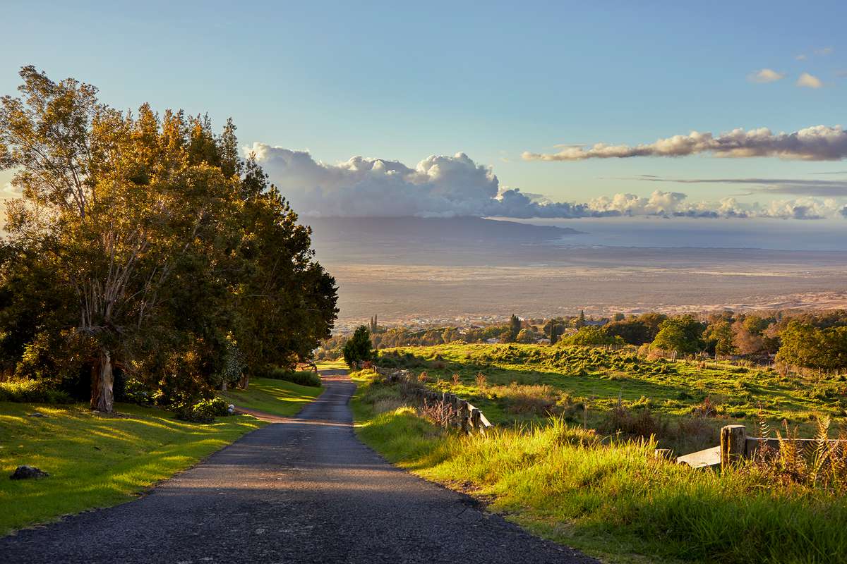 A back road in Maui’s Upcountry yields a sunset view down the slopes of Haleakalā, the larger of the two volcanoes