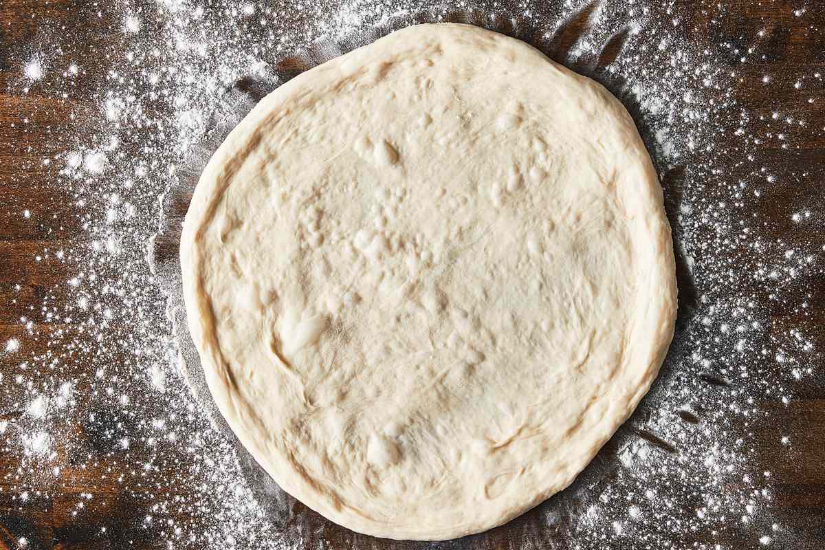pizza dough round on lightly floured surface
