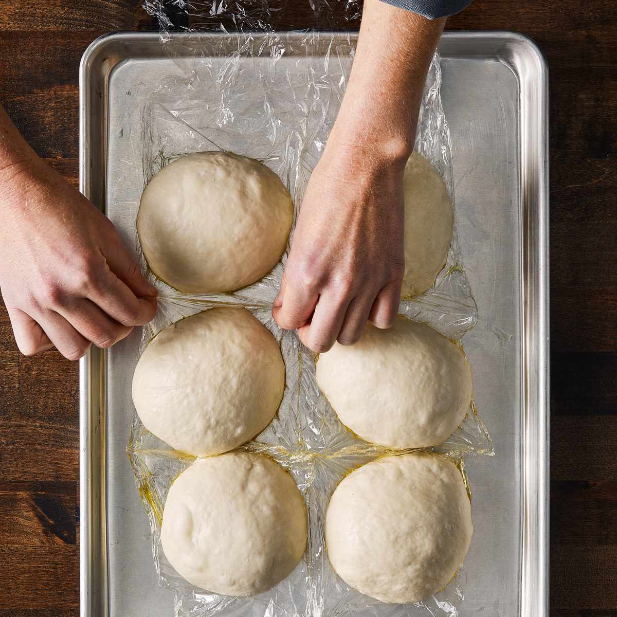 Pizza dough balls on plastic-lined, oiled sheet tray