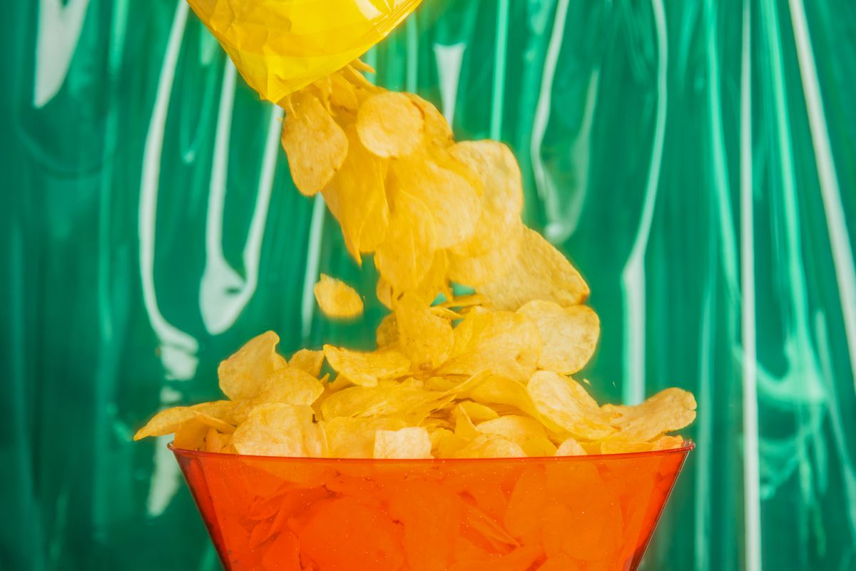 Pouring a bag of potato chips into a bowl