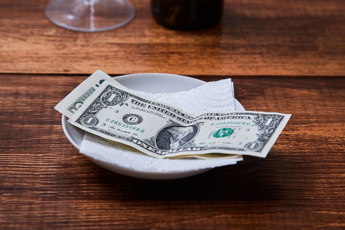 A cash tip left on a plate on a restaurant table