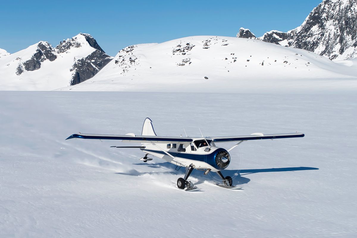 Small bush plane with skiis landing on snow in Southeast Alaska