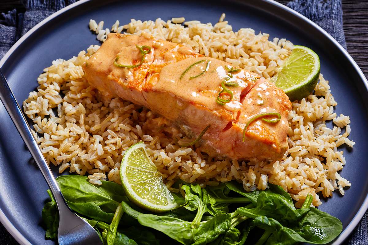 Salmon with a chili mayo sauce over rice with lime and spinach