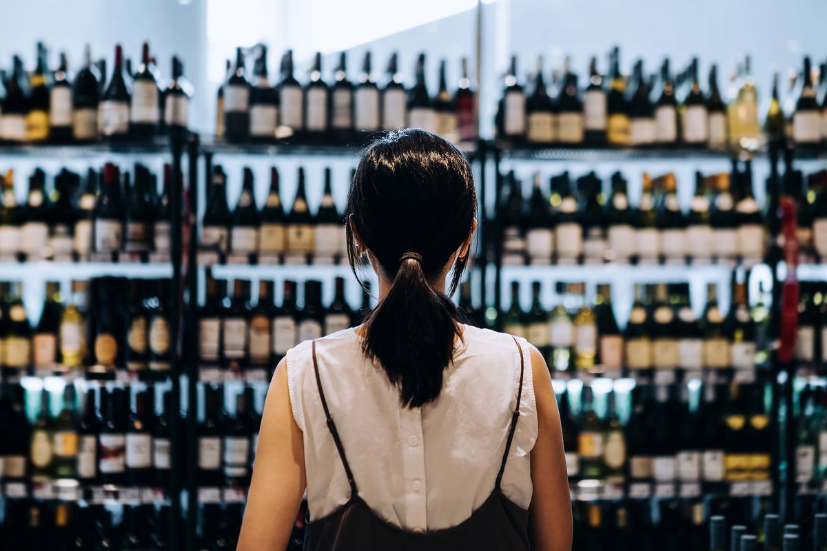 A person faces a large display of wine