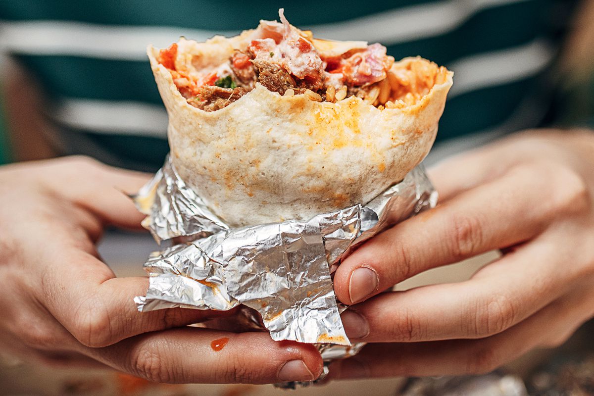 A person holds a messy burrito