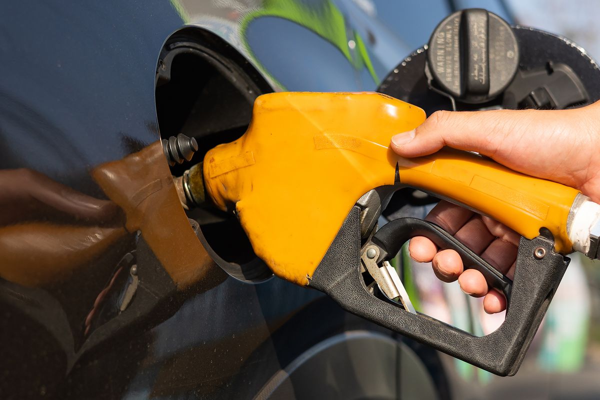 A person holds a gas nozzle as they pump gas
