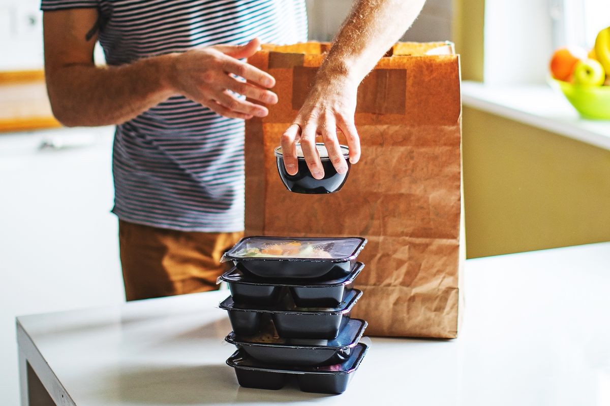 A person unpacks a food delivery in their kitchen