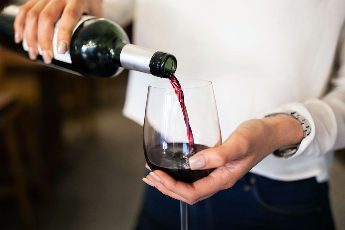 A sommelier pours grenache wine into a glass
