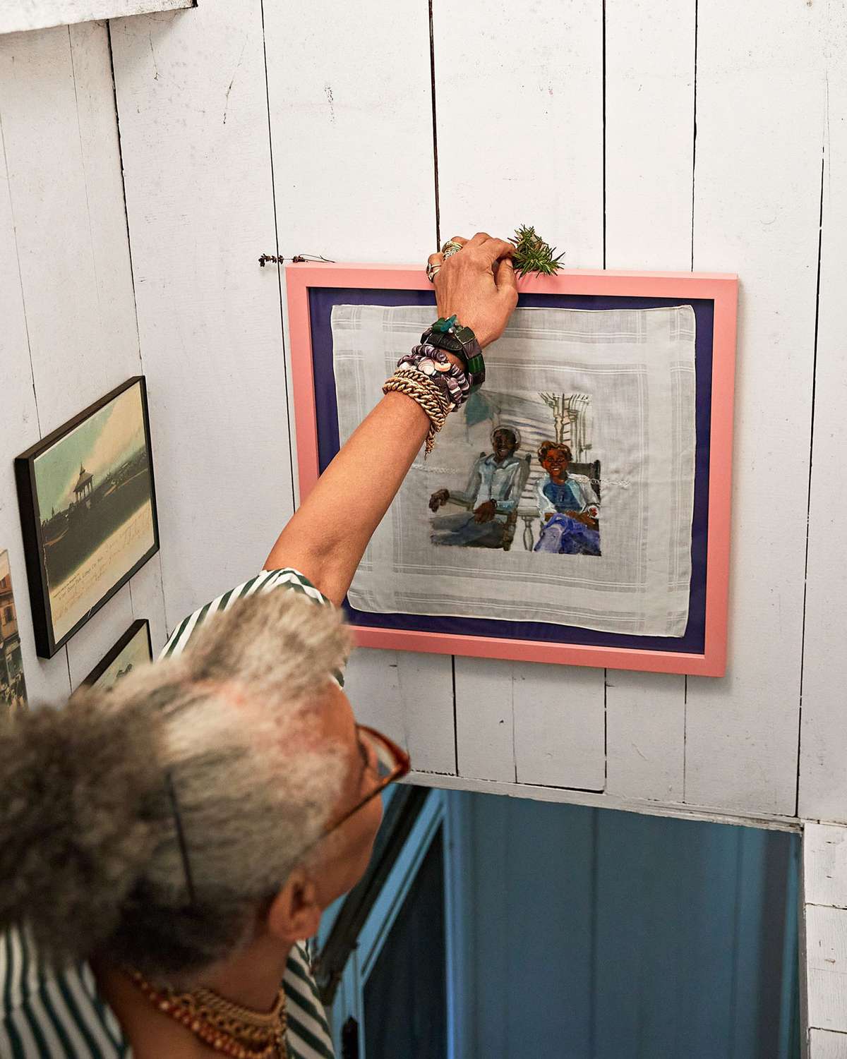 Jessica B. Harris places a sprig of rosemary above a painting of her parents in the stairwell