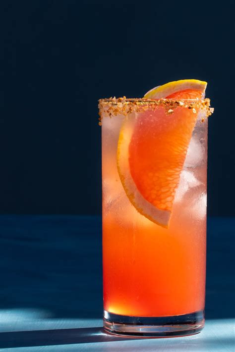Pour tequila, agave, lime juice and pink grapefruit soda in a highball classic paloma cocktail recipe