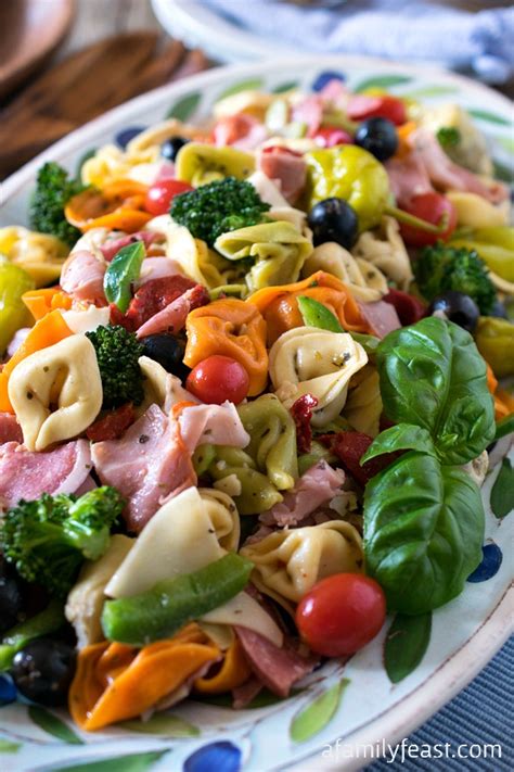 , in a large bowl combine tortellini, bell pepper, olives, tomatoes, ham, salami, antipasto tortellini pasta salad